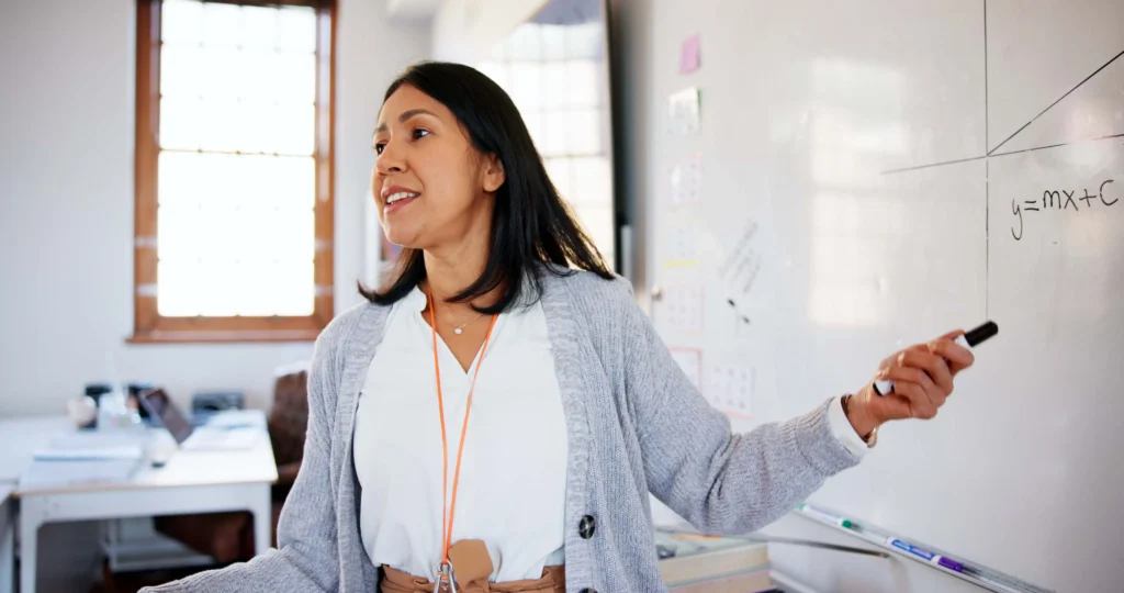 Female teacher pointing at white board